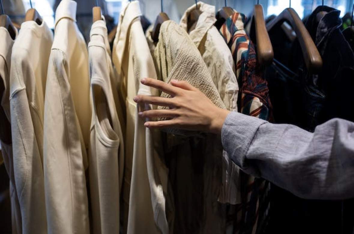 A person’s hand touching hanging clothes
