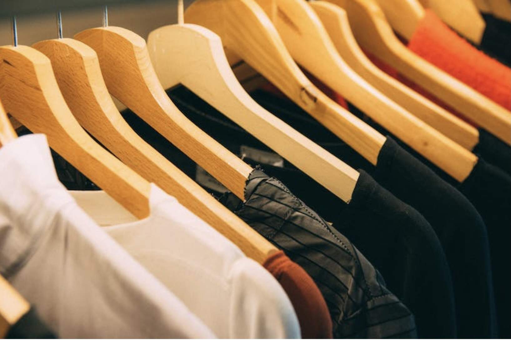 Various shirts on wooden hangers.