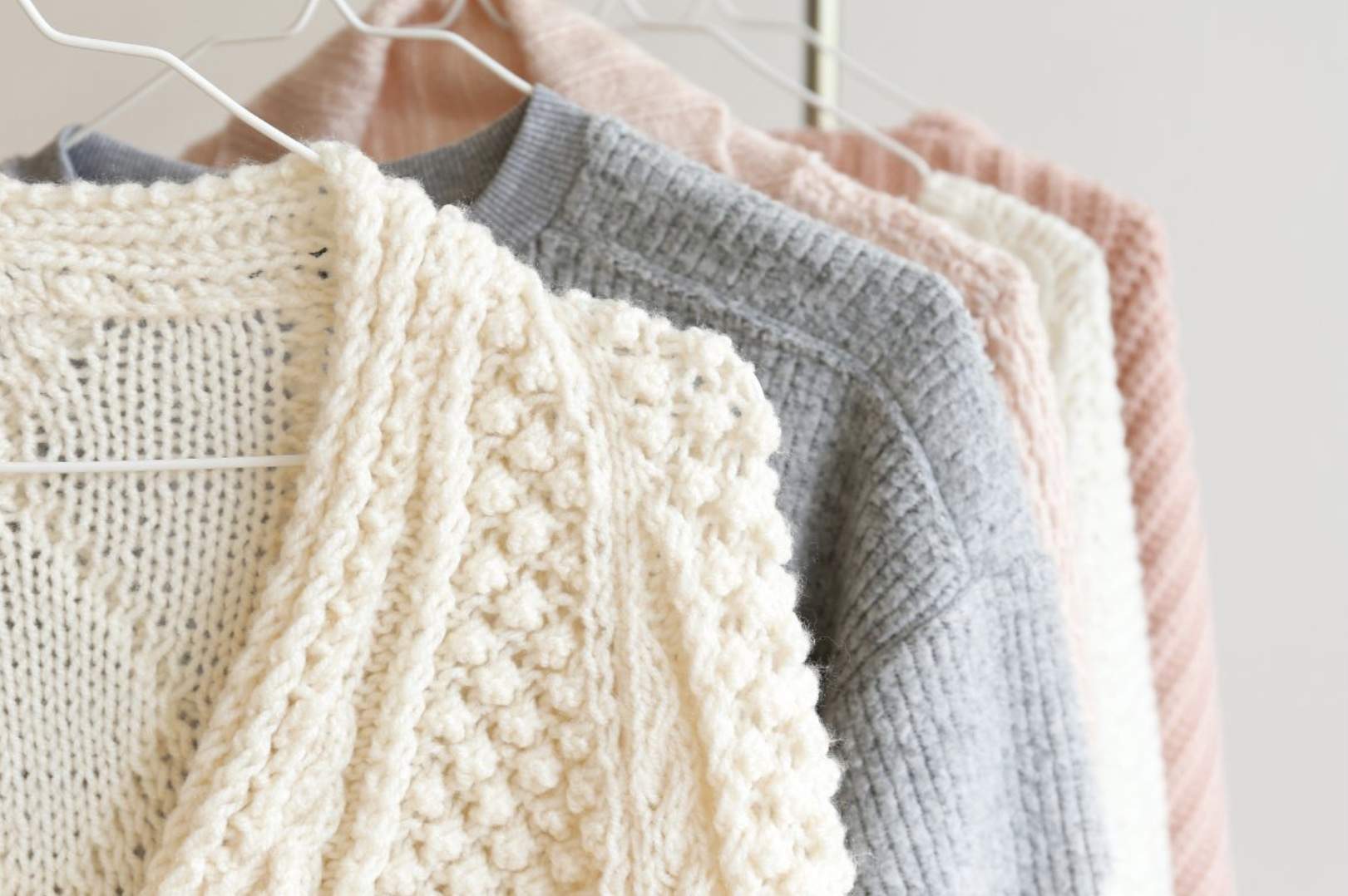 Winter sweaters hanging in the closet.